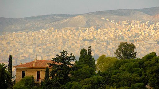 Athens, Greece, with a single building in the foreground and thousands of buildings on a mountainside in the background