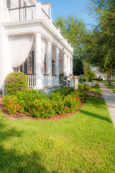 white-columned front porch in Celebration, Florida with flowing white curtains overlooking shady sidewalk