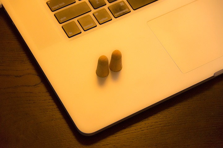 a pair of orange earplugs sit quietly on a laptop