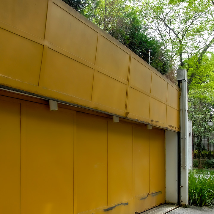 steel paneled garage door in São Paulo neighborhood with electric fence above