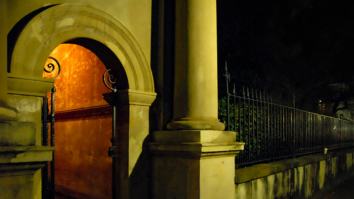 arched passage into College of Charleston campus illuminated at night