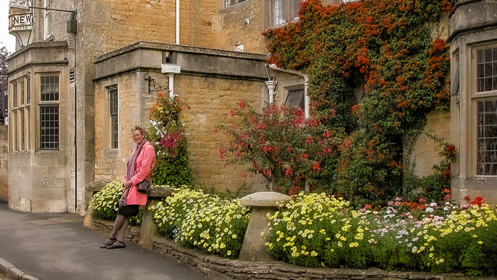 Wanda Mouzon resting against bollard in front of the New Old Inn in Bourton-On-The-Water, England