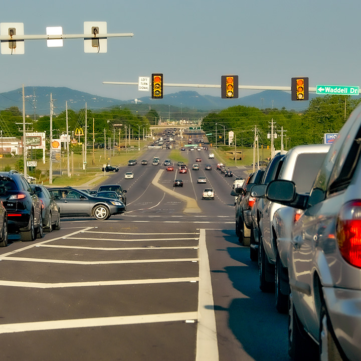 arterial traffic waiting to proceed while cross street driver blocks the intersection