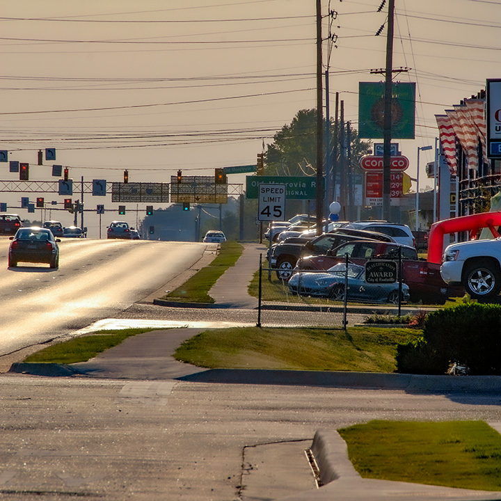 deserted sidewalk between arterial thoroughfare and parking lot