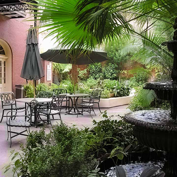 classic New Orleans French Quarter courtyard with fountain, tables, and umbrellas