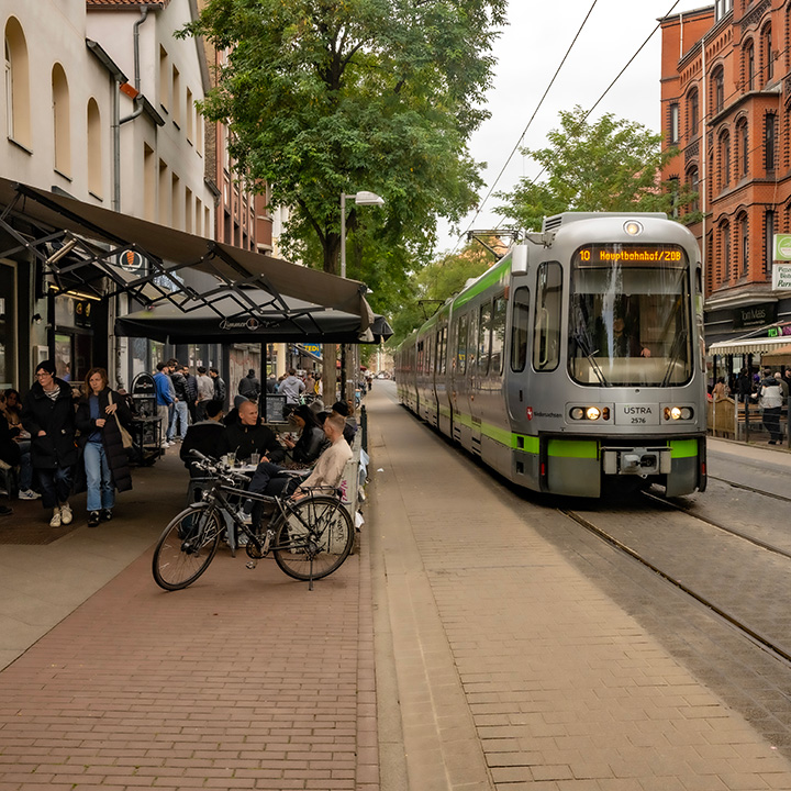 clientele sitting at sidewalk cafe in Hannover, Germany as electric tram pulls up for a stop