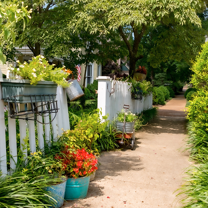 a simple Gift to the Street made up of a fence fronted by flower pots along a sidewalk