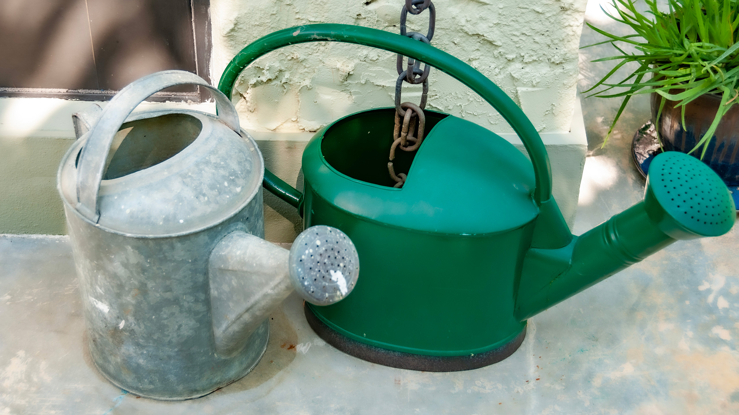 two garden watering buckets, one drawing water from a rain chain
