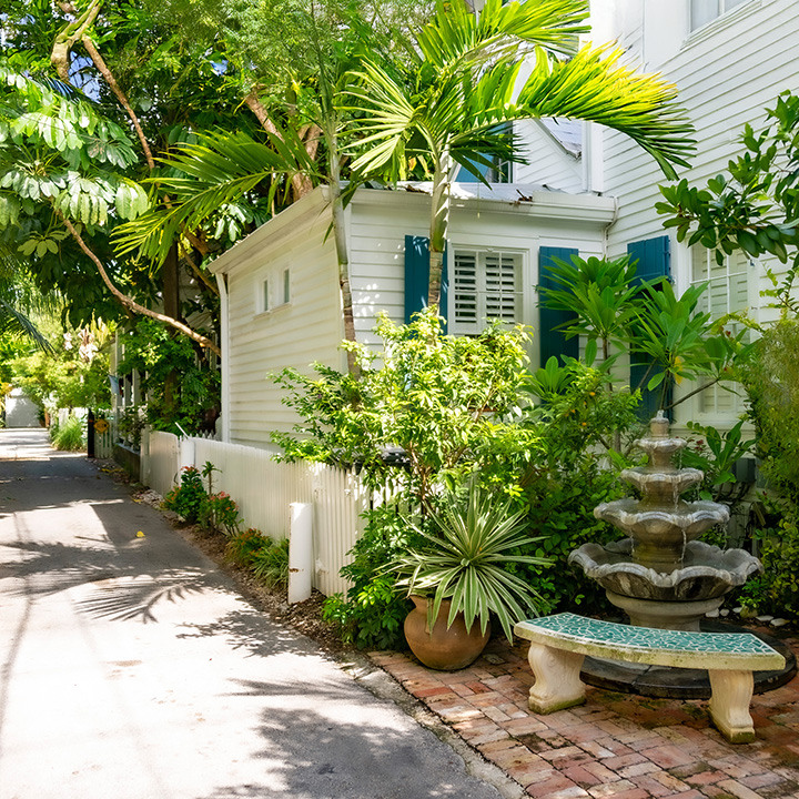 fountain, frontage garden, and bench sit beside Key West rear lane